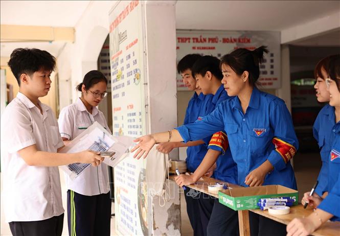 Thanh niên tình nguyện hướng dẫn thí sinh để vật dụng các nhân bên ngoài phòng thi theo quy định. Ảnh: Thanh Tùng - TTXVN