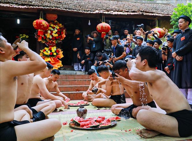 Nghi thức uống rượu, ăn dưa trước khi trận vật cầu nước diễn ra. Ảnh: Khánh Hoà - TTXVN