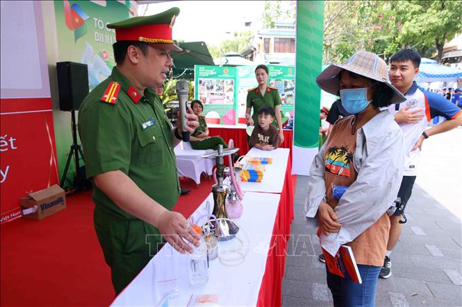 Người dân được các chiến sĩ Công an Thủ đô tuyên truyền về tác hại và cách phòng, chống ma tuý tại buổi lễ. Ảnh: Phạm Kiên - TTXVN