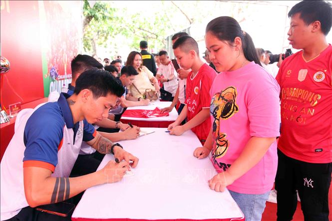 Người dân và các em nhỏ hào hứng giao lưu, xin chữ ký các cầu thủ CLB bóng đá Công an Hà Nội tại buổi lễ. Ảnh: Phạm Kiên - TTXVN