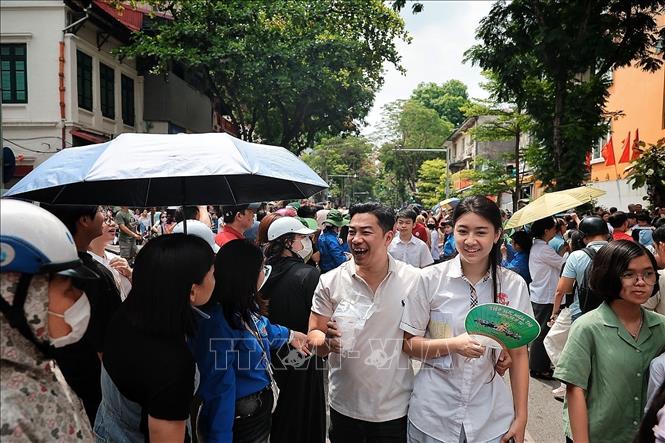 Nụ cười nhẹ nhõm của phụ huynh và thí sinh sau giờ thi, giữa vòng tay tiếp sức của các tình nguyện viên trước cổng trường. Ảnh: Phạm Tuấn Anh - TTXVN