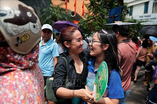 Hai mẹ con tươi cười phấn khởi sau khi thí sinh hoàn thành tốt mô thi đầu tiên, tại điểm thi Trường THCS Ngô Sĩ Liên. Ảnh: Phạm Tuấn Anh - TTXVN