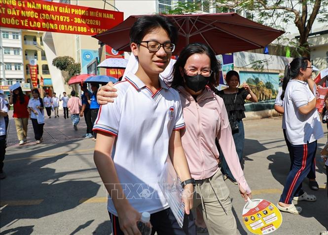 Chia sẻ cảm xúc với con sau khi hoàn thành môn thi Ngoại ngữ tại điểm thi trường THCS Ngô Quyền (phường Bạch Mai). Ảnh: Khánh Hoà - TTXVN