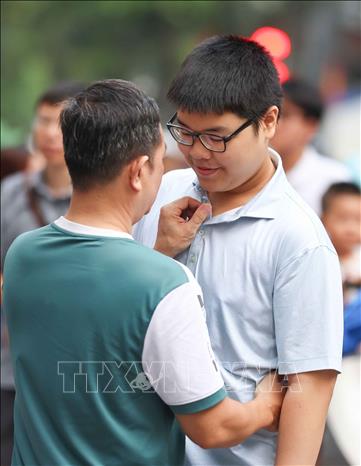 Động viên con trai vững tin trước mỗi môn thi. Ảnh: Thanh Tùng - TTXVN