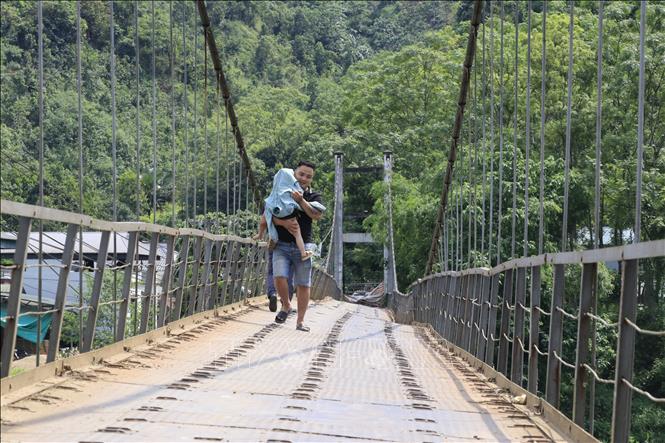 Người dân hàng ngày vẫn liều mình đi bộ qua cầu treo Yên Phú. Ảnh: Đinh Thùy - TTXVN