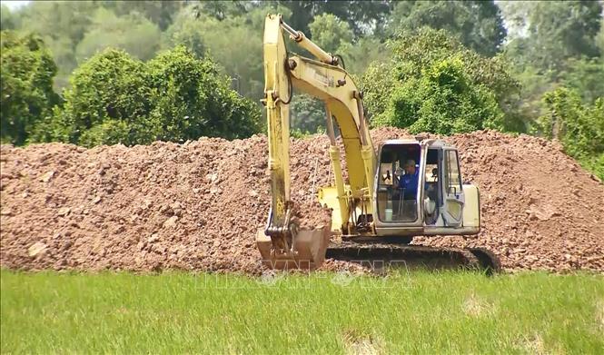 Máy móc đắp bờ bao để bơm cát san lấp mặt bằng, thi công Dự án trường Phổ thông nội trú Tiểu học - Trung học cơ sở Tân Hộ Cơ (xã Tân Hộ Cơ). Ảnh: Nhựt An - TTXVN 