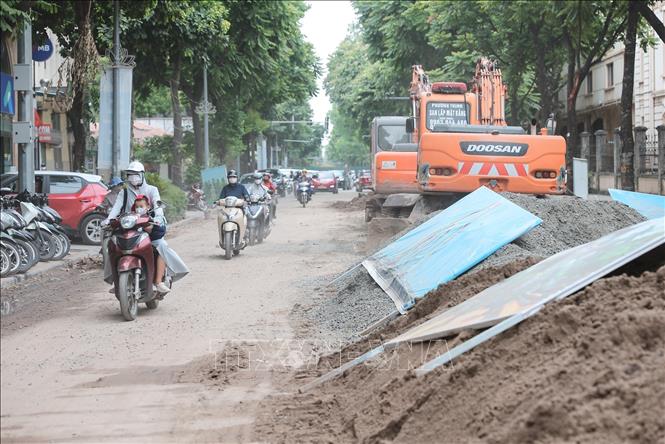 Bụi từ công trường thi công cống ngầm trên phố Quang Trung ảnh hưởng đến tầm nhìn, khiến người tham gia giao thông phải che chắn và di chuyển thận trọng. Ảnh: Lê Đông - TTXVN