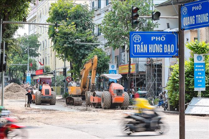 Công nhân cùng hệ thống máy móc chuyên dụng đang khẩn trương sớm hoàn thiện và hoàn trả mặt đường tại ngã tư Quang Trung - Trần Hưng Đạo. Ảnh: Lê Đông - TTXVN