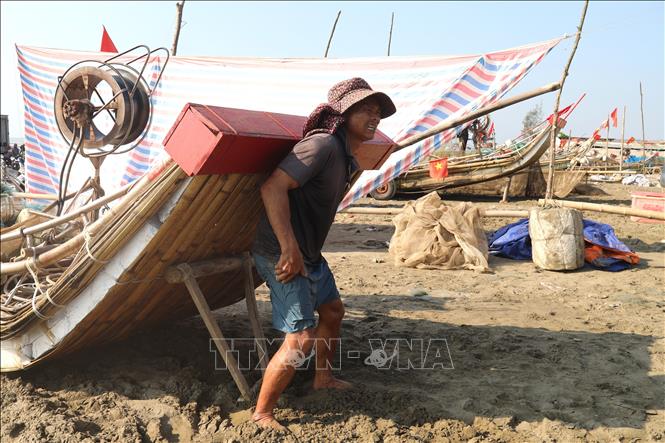 Ngư dân làng biển Tiền Tiến (xã Hải Châu, tỉnh Nghệ An) vất vả dùng lưng nâng cao mũi bè mảng trong thời tiết giữa trưa nắng để chuẩn bị ra khơi. Ảnh: Xuân Tiến - TTXVN 
