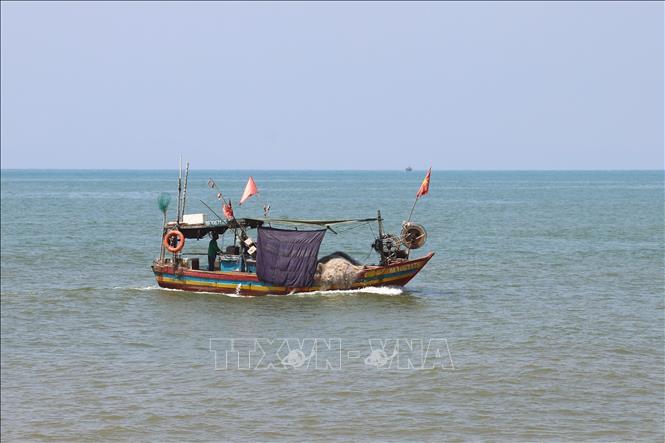 Ngư dân xã Quỳnh Phú (tỉnh Nghệ An) căng những tấm vải che ánh nắng mặt trời chiếu rọi vào khu vực để hải sản trên khoang thuyền khi chạy vào cửa biển Lạch Quèn, vào khu neo đậu. Ảnh: Xuân Tiến - TTXVN 
