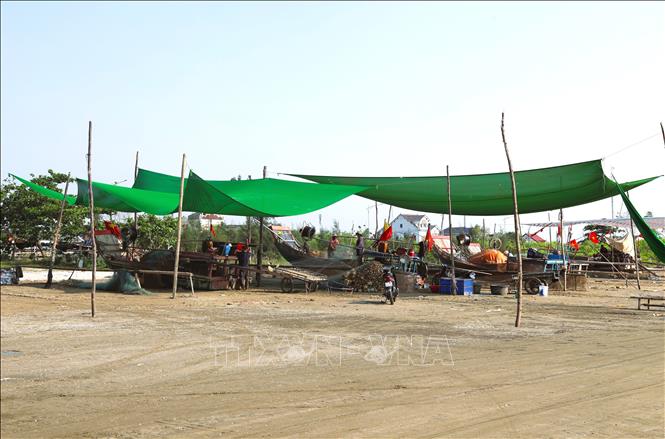 Ngư dân các làng biển xã Hải Châu (tỉnh Nghệ An) căng những tấm vải rộng để bảo vệ bè mảng, ngư lưới cụ và tạo bóng mát, hạn chế nắng nóng khi gỡ cá khỏi lưới. Ảnh: Xuân Tiến - TTXVN 