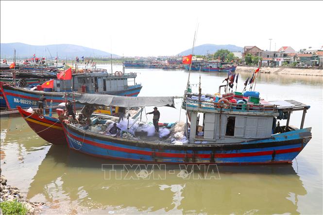 Ngư dân Nghệ An căng phông bạt tạo bóng mát trên khoang tàu cá trong lúc chuẩn bị ngư lưới cụ trước khi vươn khơi. Ảnh: Xuân Tiến - TTXVN 
