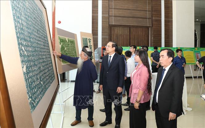 Visitors learn about the cliff-based inscriptions on Non Nuoc Mountain. VNA Photo