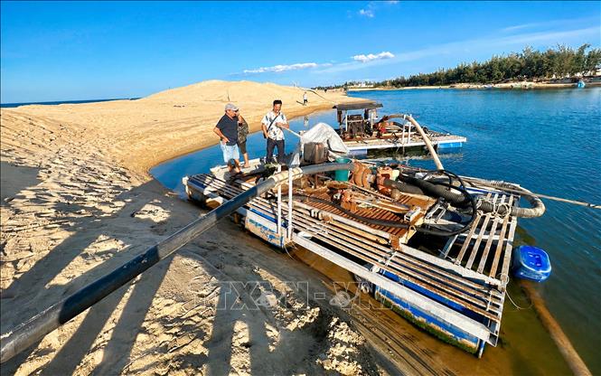 Chính quyền xã Đông Trạch, tỉnh Quảng Trị huy động lực lượng và phương tiện nạo vét, mở tuyến luồng tạm xuyên qua cồn cát tại cửa biển Lý Hòa nhằm khơi thông dòng chảy, tạo điều kiện cho tàu thuyền ra vào và tăng khả năng tiêu thoát nước. Ảnh: Nguyên Linh - TTXVN