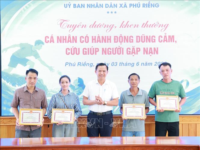 Lãnh đạo xã Phú Riềng khen thưởng cho cá nhân đã kịp thời cứu người do lũ. Ảnh: TTXVN phát