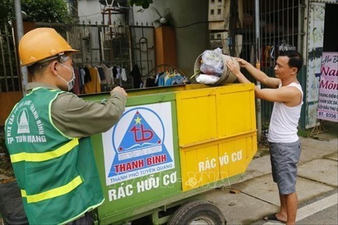 Công nhân Hợp tác xã Vận tải và Dịch vụ môi trường Thanh Bình (xã Lưỡng Vượng, thành Phố Tuyên Quang, tỉnh Tuyên Quang) hướng dẫn người dân phân loại rác trực tiếp trong quá trình thu gom. Việc thu gom, phân loại và tái chế rác thải nhựa của HTX đã giải quyết lượng rác thải nhựa đang ngày một tăng cao ngoài môi trường. Ảnh: Nam Sương - TTXVN