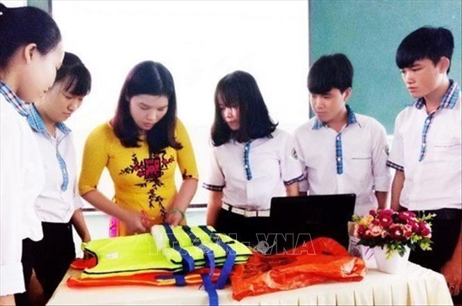 Cô giáo Mai Thùy Hân (Quảng Bình) hướng dẫn học sinh làm sản phẩm tái chế từ rác thải thành đồ dùng hữu ích cho cuộc sống. Ảnh: Võ Thị Dung - TTXVN