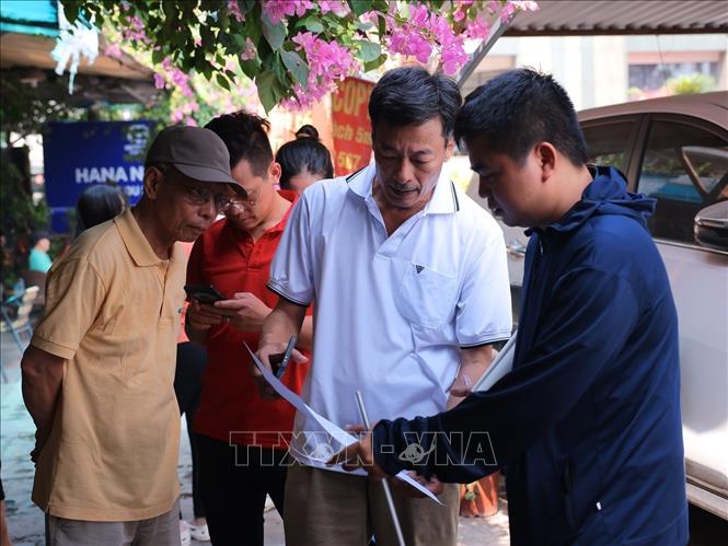 Ông Trần Mạnh Hùng (áo trắng) chủ nhà số 6 Đường Giải Phóng là 1 trong những hộ dân thuộc khu vực GPMB mở rộng tuyến Quốc lộ 1 đang trao đổi với nhân viên đo đạc về diện tích đất sở hữu. Ảnh: Hoàng Hiếu - TTXVN