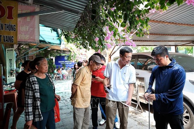 Các hộ dân trao đổi thông tin với nhân viên đo đạc về hiện trạng thửa đất giúp ghi nhận thông tin ban đầu tại khu vực dự kiến giải phóng mặt bằng. Ảnh: Phạm Tuấn Anh - TTXVN