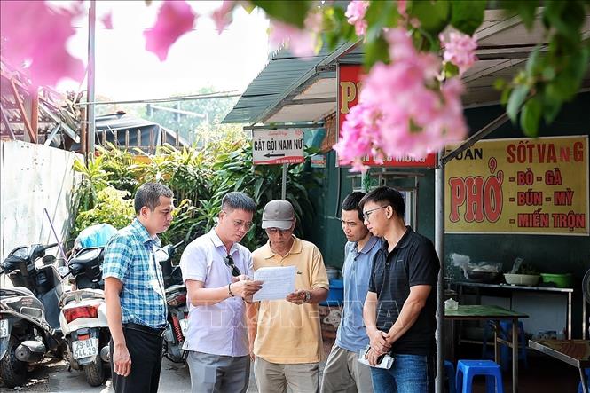 Ông Nguyễn Tuấn Anh, Trưởng bộ phận quản lý dự án phường Kim Liên (áo tím từ trái sang) hướng dẫn người dân kê khai diện tích đất. Ảnh: Phạm Tuấn Anh - TTXVN