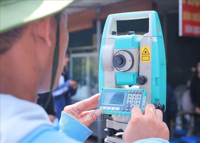 Nhân viên đo đạc sử dụng máy toàn đạc để xác định mốc, thu thập số liệu hiện trạng tại khu vực tổ 75, phường Kim Liên. Ảnh: Hoàng Hiếu - TTXVN
