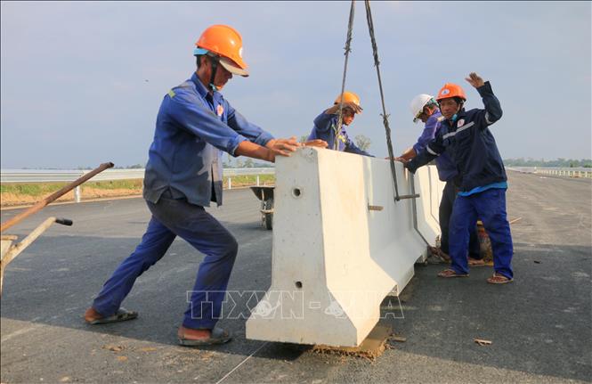 Công nhân lắp đặt dải phân cách tại gói thầu 44, tuyến cao tốc Châu Đốc - Cần Thơ - Sóc Trăng, đoạn qua xã Vĩnh Hanh, tỉnh An Giang. Ảnh: Công Mạo-TTXVN