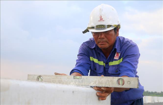 Công nhân lắp đặt dải phân cách tại gói thầu 44, tuyến cao tốc Châu Đốc - Cần Thơ - Sóc Trăng, đoạn qua xã Vĩnh Hanh, tỉnh An Giang. Ảnh: Công Mạo - TTXVN
