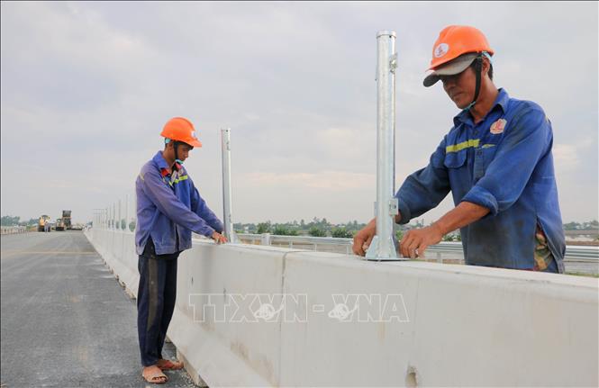 Công nhân lắp đặt hệ thống an toàn giao thông tại gói thầu 44, tuyến cao tốc Châu Đốc - Cần Thơ - Sóc Trăng, đoạn qua xã Vĩnh Hanh, tỉnh An Giang. Ảnh: Công Mạo - TTXVN