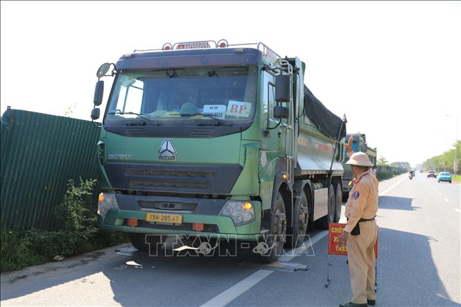 Tổ công tác của Đội Cảnh sát giao thông đường bộ số 10, Phòng Cảnh sát giao thông dừng xem để kiểm tra tải trọng xe. Ảnh: Quốc Lũy - TTXVN