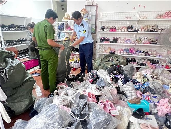 Các lực lượng chức năng phát hiện các sản phẩm giày dép có dấu hiệu xâm phạm sở hữu công nghiệp của các thương hiệu được bảo hộ lớn tại cửa hàng Bin Heo. Ảnh: TTXVN phát
