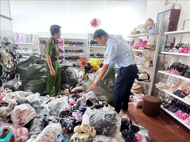 Các lực lượng chức năng phát hiện các sản phẩm giày dép có dấu hiệu xâm phạm sở hữu công nghiệp của các thương hiệu được bảo hộ lớn tại cửa hàng Bin Heo. Ảnh: TTXVN phát