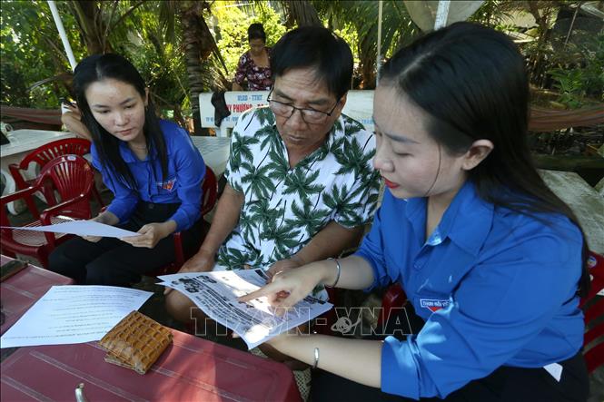 Đoàn viên thành niên phường Vị Tân, thành phố Cần Thơ hướng dẫn người dân sử dụng ứng dụng VneID, định danh điện tử và các tiện ích số trong đời sống xã hội trong chiến dịch mùa hè số cùng VneID. Ảnh: Duy Khương – TTXVN