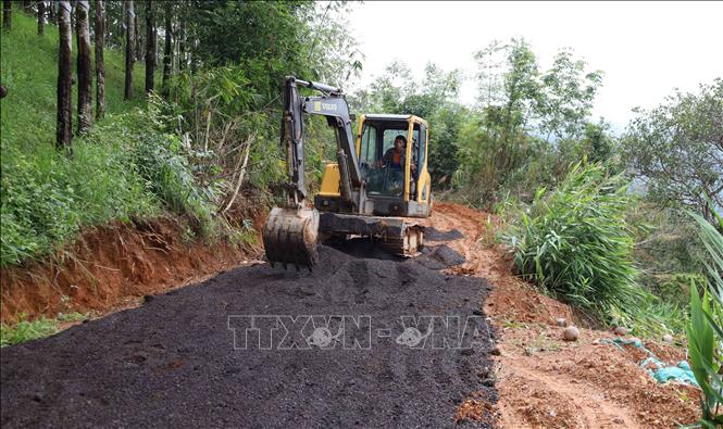 Mỗi hộ gia đình đóng ít nhất 3 triệu đồng để thuê máy múc san gạt mặt bằng, đào mương thoát nước, đổ đá dăm gia cố các đoạn đường xuống cấp nghiêm trọng. Ảnh: Đậu Tất Thành – TTXVN.