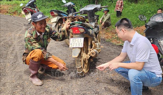 Anh Nguyễn Thanh Văn (đội nón bên trái), thôn Sơn Phú, xã Thọ Sơn, thành phố Đồng Nai cho biết, mùa mưa, anh Văn phải lắp xích chống trượt vào bánh xe mới lưu thông được qua tuyến đường Bà Lan. Ảnh: Đậu Tất Thành – TTXVN.