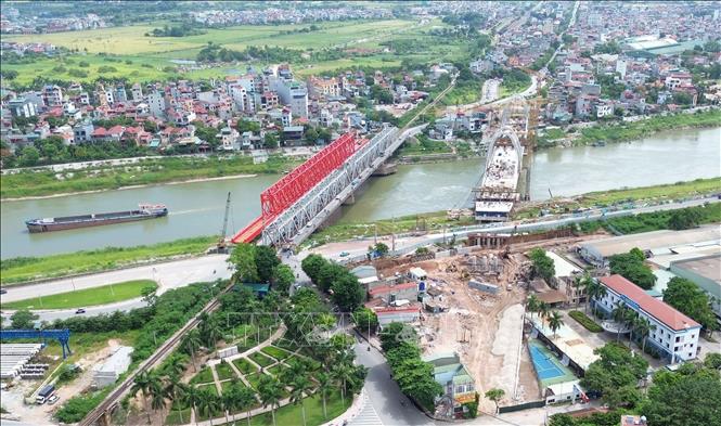 Khi hoàn thành, cầu Đuống mới sẽ tách riêng luồng đường sắt (đỏ, bên trái, sát cầu Đuống cũ) và đường bộ (bên phải), tăng năng lực vận tải thủy và tạo thêm trục kết nối quan trọng giữa nội đô với khu vực phía Đông Bắc Thủ đô. Ảnh: Quốc Khánh - TTXVN
