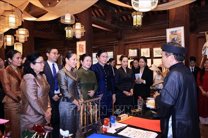 Các Phu nhân nghe giới thiệu về nghệ thuật thư pháp của Việt Nam. Ảnh: Tuấn Anh - TTXVN