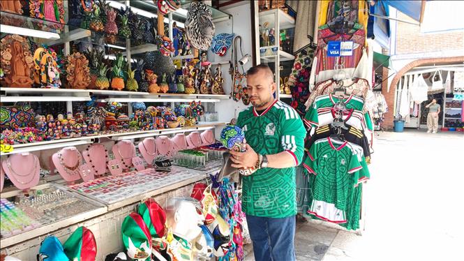 Chủ cửa hàng chỉnh trang mô hình cúp FIFA World Cup 2026 mang đậm sắc màu nghệ thuật thủ công Huichol truyền thống của Mexico. Ảnh: Phương Lan- PV TTXVN tại Mexico 