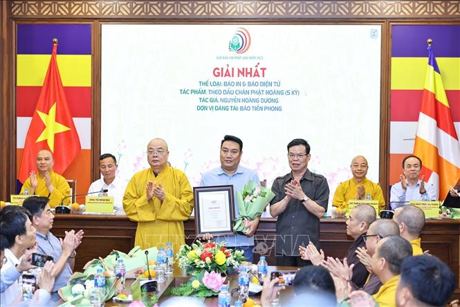 Phó Trưởng ban Tuyên giáo và Dân vận Trung ương Triệu Tài Vinh, Hòa thượng Thích Thanh Nhiễu, Phó Chủ tịch Thường trực Hội đồng trị sự trao giải Nhất thể loại Báo in và Báo điện tử cho tác giả Nguyễn Hoàng Dương với tác phẩm Theo dấu chân Phật hoàng. Ảnh: Minh Đức – TTXVN