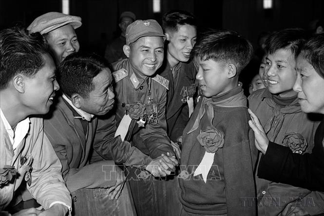 Các đại biểu tại Đại hội Anh hùng, Chiến sĩ thi đua toàn quốc lần thứ IV (1966) thăm hỏi em Hoa Xuân Tứ, học sinh lớp 6 (Nghệ An), bị khuyết tật  cả hai tay vẫn nỗ lực học tập, trở thành “Cháu ngoan Bác Hồ” và kiện tướng về thể dục. Ảnh: TTXVN