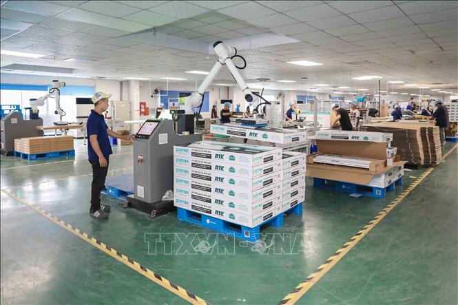 Cánh tay robot thực hiện thao tác gắp, xếp các hộp sản phẩm đèn LED lên pallet, giúp tự động hóa quy trình đóng gói và nâng cao hiệu suất làm việc. Ảnh: Phan Phương - TTXVN