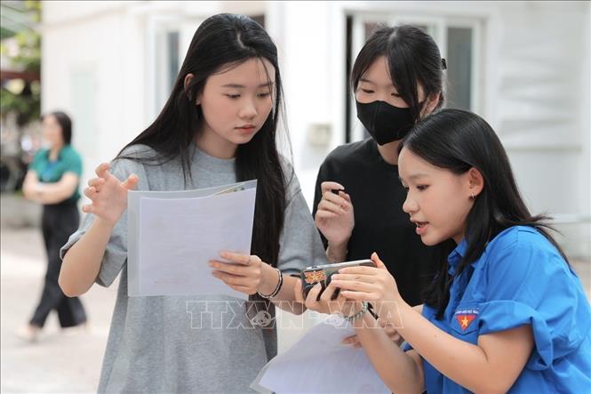 Tình nguyện viên hỗ trợ thí sinh đến làm thủ tục dự thi tại điểm thi Trường THPT Nguyễn Gia Thiều (Hà Nội). Ảnh: Minh Quyết - TTXVN