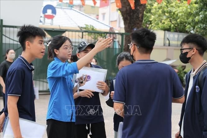Tình nguyện viên hỗ trợ thí sinh đến làm thủ tục dự thi tại điểm thi Trường THPT Nguyễn Gia Thiều (Hà Nội). Ảnh: Minh Quyết - TTXVN