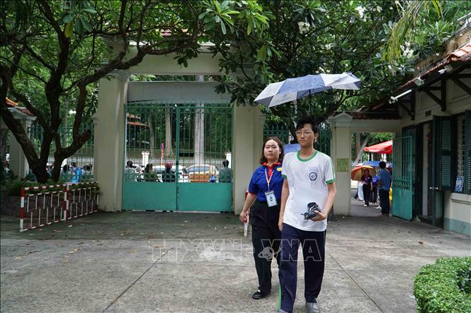 Tình nguyện viên hỗ trợ thí sinh vào phòng tại điểm thi Trường THPT Lê Quý Đôn. Ảnh: Thu Hoài - TTXVN