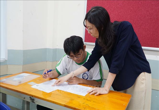 Cán bộ coi thi hướng dẫn thí sinh kiểm tra thông tin. Ảnh: Thu Hoài - TTXVN