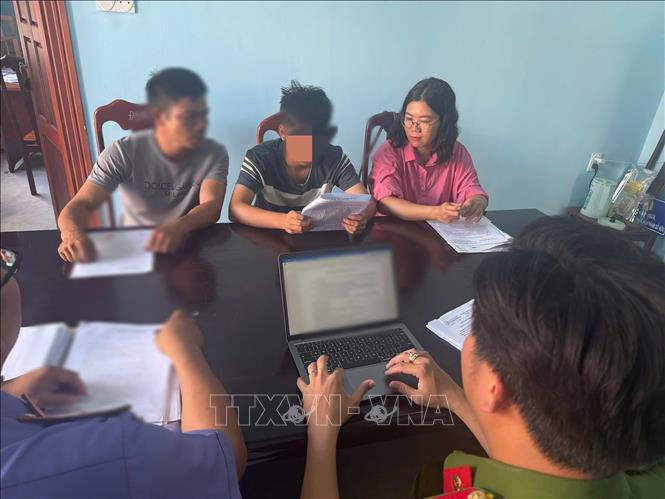 Nam sinh lớp 10 N.H.A. cùng người giám hộ làm việc với cơ quan điều tra. Ảnh: TTXVN phát