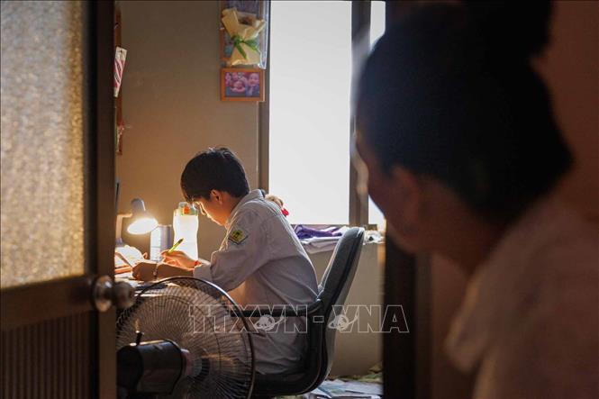 Mẹ lặng lẽ đứng phía sau cánh cửa nhìn con học bài. Trong mùa thi, có những yêu thương được gửi đi bằng sự im lặng để con yên tâm tập trung. Ảnh: Phạm Tuấn Anh - TTXVN
