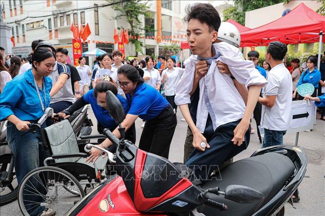 Sau khi kết thúc môn Ngữ văn, bố bế Sơn từ xe lăn lên xe máy - động tác quen thuộc suốt 18 năm qua đồng hành cùng con. Ảnh: Phạm Tuấn Anh - TTXVN