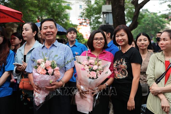 Các phụ huynh chuẩn bị hoa để tặng cho các thí sinh sau khi hoàn thành môn Toán. Ảnh: Phạm Tuấn Anh - TTXVN