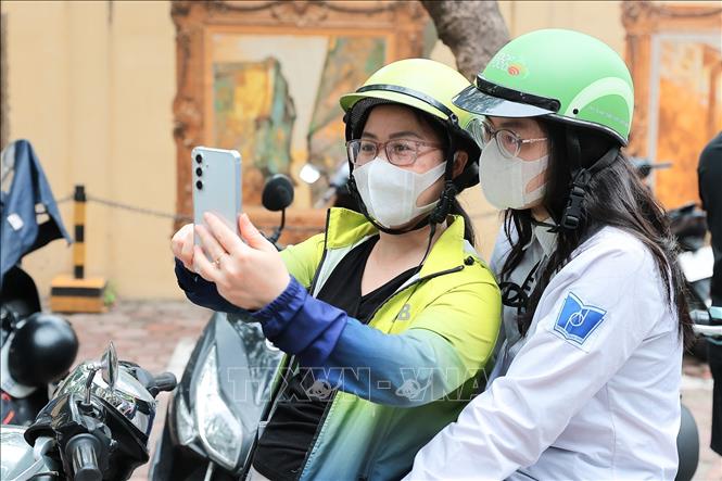 Phụ huynh và thí sinh tranh thủ chụp ảnh selfie trước cổng trường thi để báo tin vui, chia sẻ cảm xúc sau khi hoàn thành ngày thi đầu tiên với người thân, tại điểm thi Trường THPT Phan Đình Phùng (Phường Ba Đình). Ảnh: Lê Đông - TTXVN