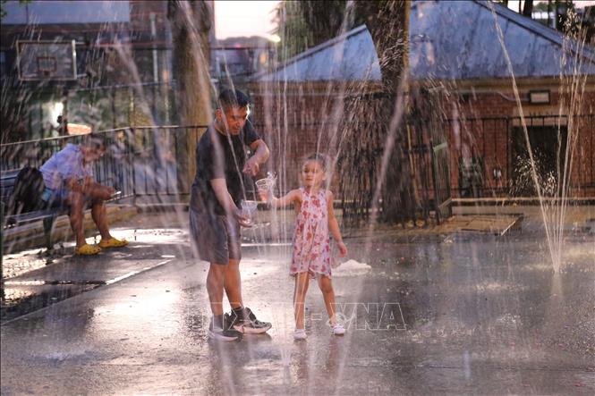 Người dân tránh nóng bên đài phun nước ở New York, Mỹ. Ảnh: THX/TTXVN